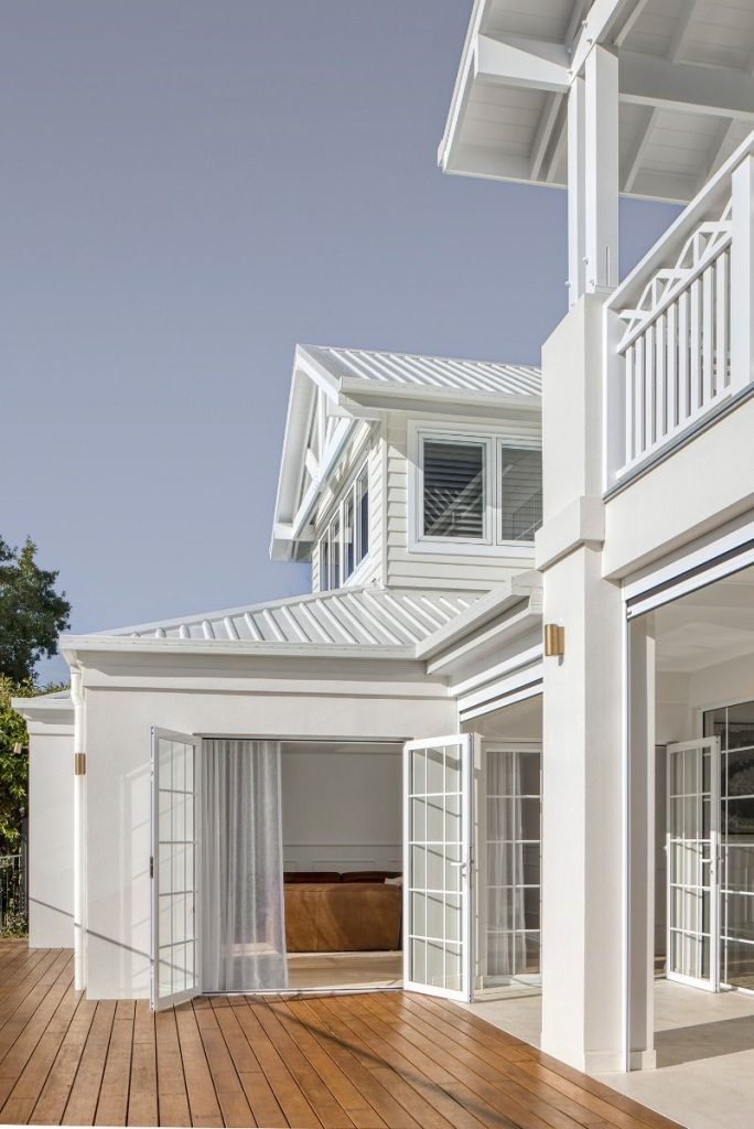 Modern coastal white house exterior with wooden deck and large windows